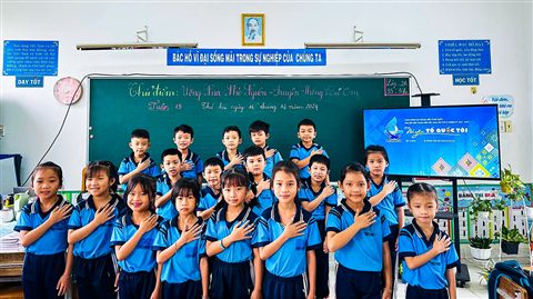 Học sinh chào cờ trong lớp học